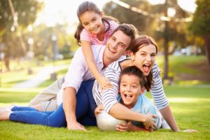 Family Lying On Grass In Park Together